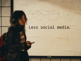 Person mit Smartphone vor Plakat mit Aufschrift "Less Social Media"
