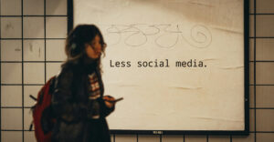 Person mit Smartphone vor Plakat mit Aufschrift "Less Social Media"