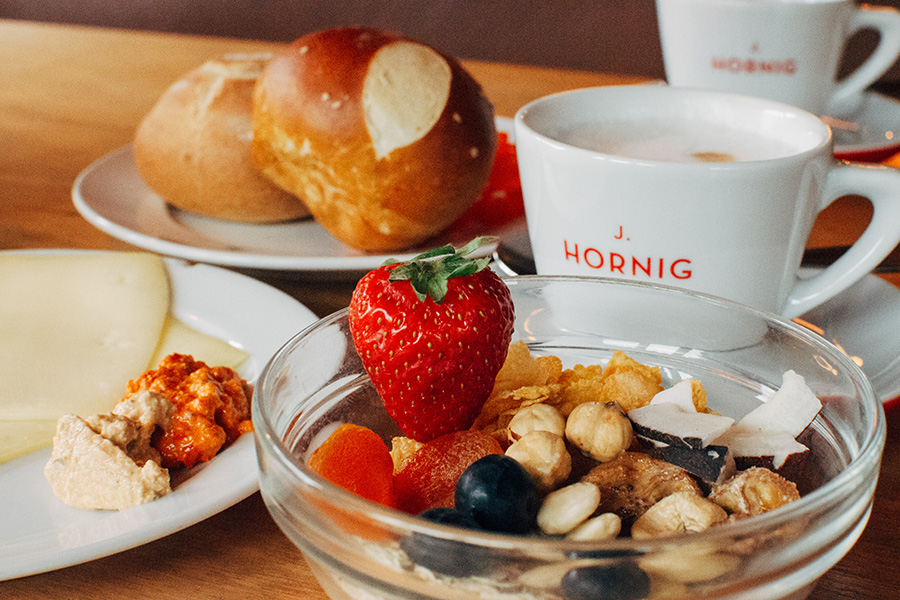 Frühstück mit Früchte-Müsli, Käse, Brötchen und Kaffee